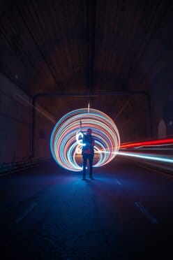 Fotograaf maakt lichtsporen met LED-lampen in een donkere tunnel tijdens lange sluitertijd.