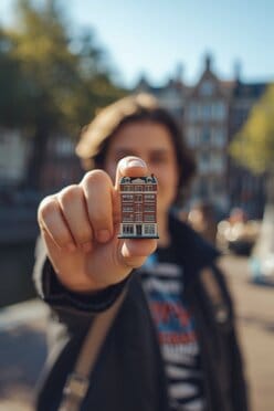 Persoon fotografeert een miniatuurgebouw in zijn hand met forced perspective in Amsterdam.